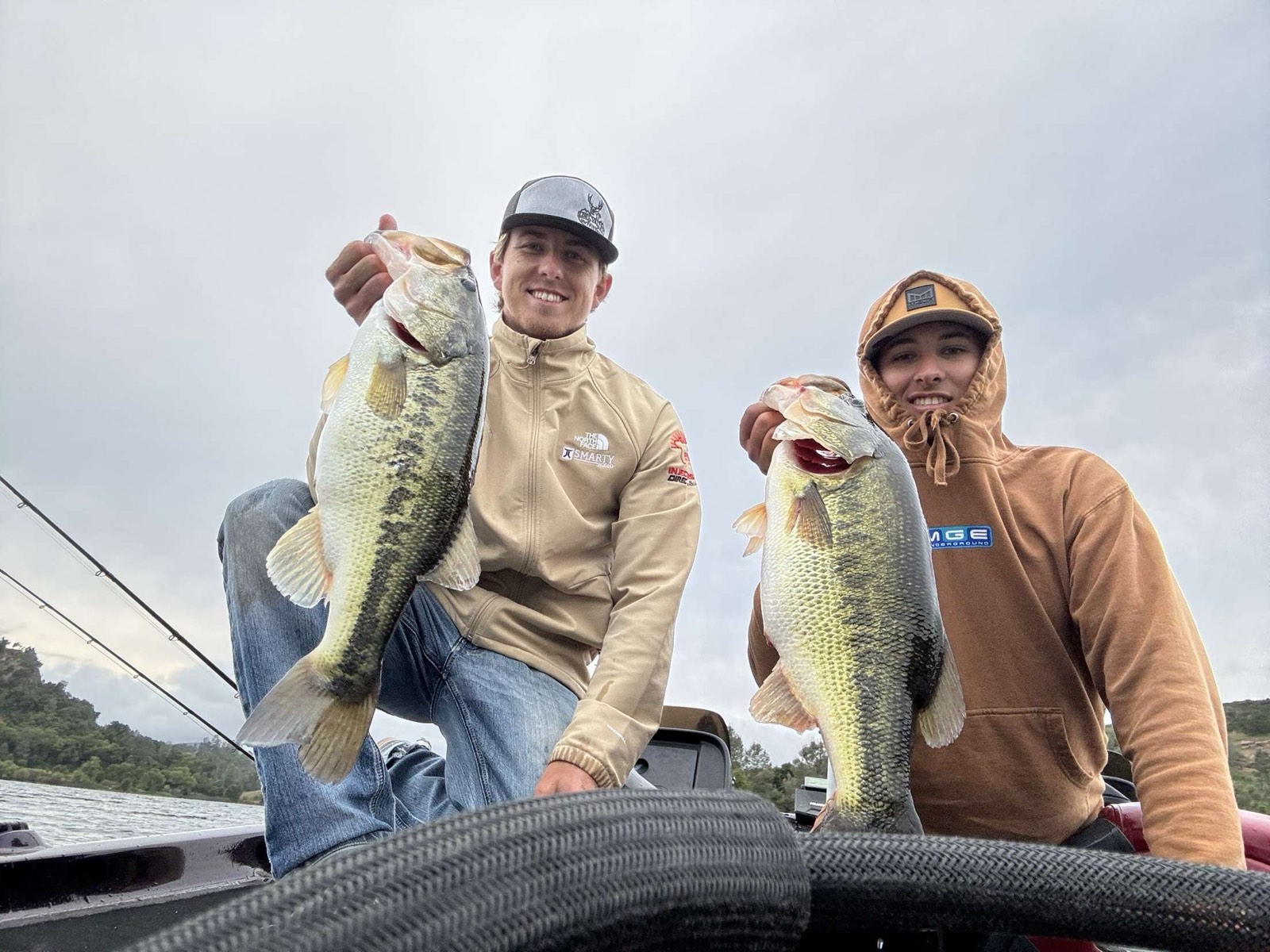 Two anglers on the boat holding large largemouth bass caught on Lake Nacimiento