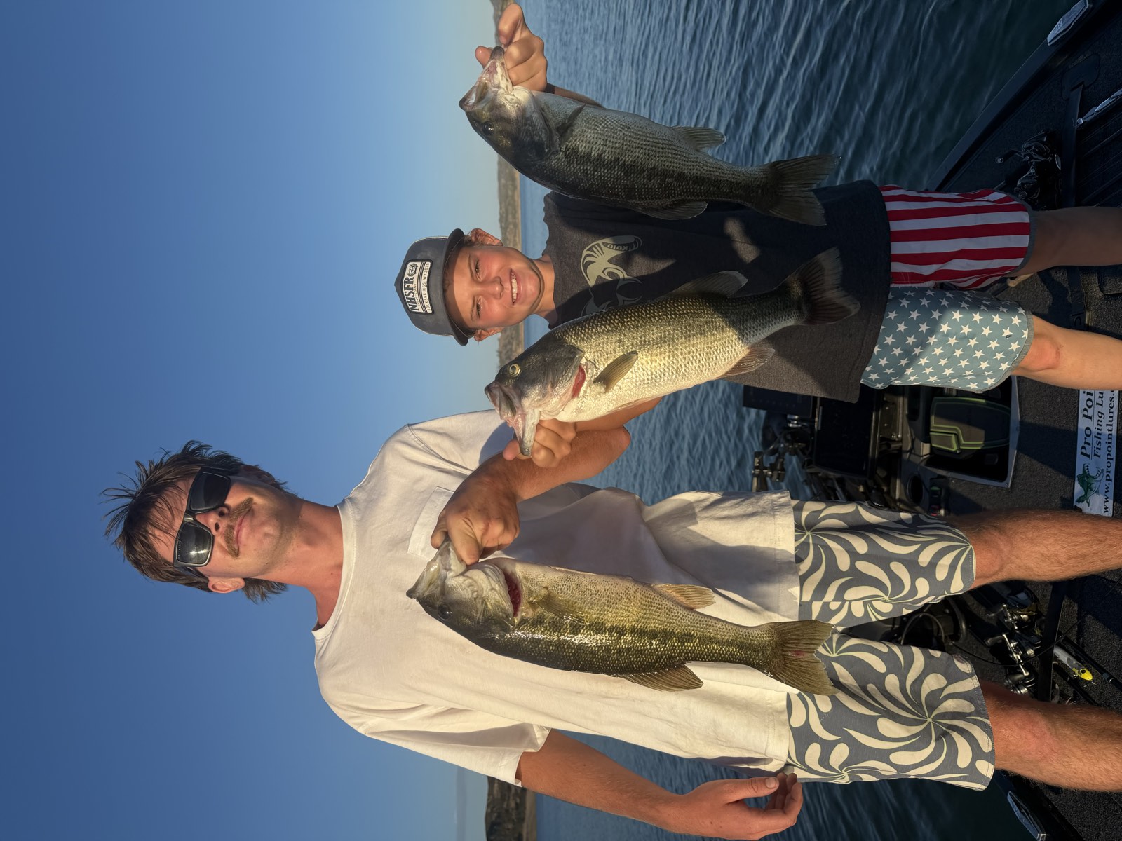 Two guests on the boat holding largemouth bass on a clear day at Lake Nacimiento